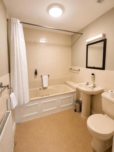 a bathroom with a tub and a toilet and a sink at The Lairgate in Beverley