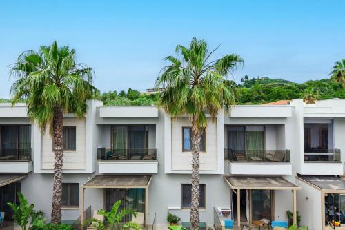 a building with palm trees in front of it at Pefki Deluxe Residences - Adults Only 16plus in Pefkochori