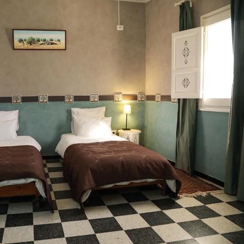 a bedroom with two beds and a window at Dar Elferdaous in Al Medou