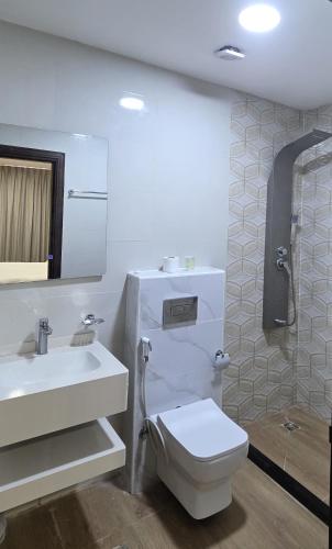 a white bathroom with a toilet and a sink at Selena Hotel Aqaba in Aqaba