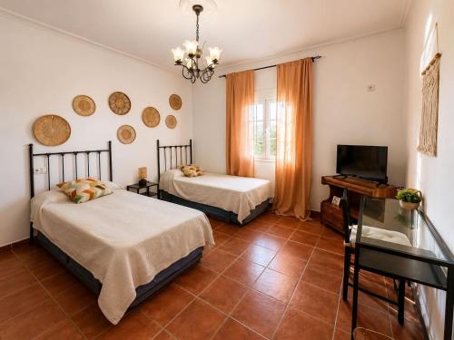 a bedroom with two beds and a tv and a window at Antigua Villa Medina casa con piscina 3 habitaciones in Marchena
