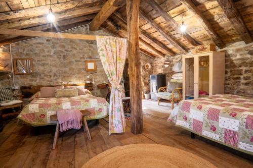 a bedroom with two beds and a stone wall at Vivienda pasiega LO LUCAS 1920 in San Roque de Ríomiera