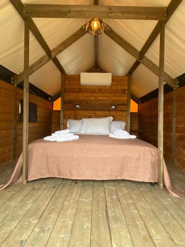 a bed in a wooden room with a ceiling at Glamping - La Giara in San Demetrio Corone