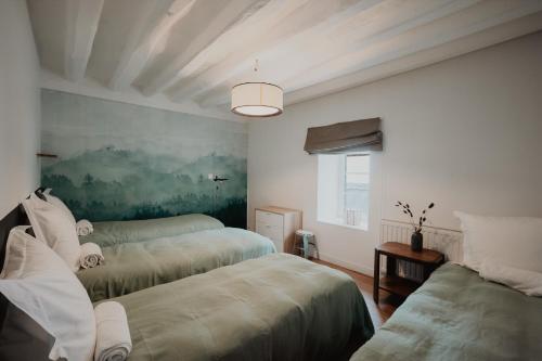 a bedroom with two beds and a painting on the wall at Le gîte de Bresteau in Beillé