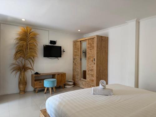a bedroom with a bed and a tv on a wall at Braban Sari Guest House Seminyak in Seminyak