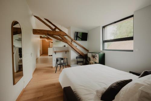 a bedroom with a white bed and a staircase at L'annexe de Bresteau in Beillé