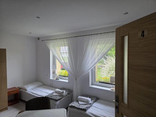 a bedroom with two beds and a window at PRZYSTANEK nowEKOprzywno - Żółty Domek Pod Kasztanem in Barwice
