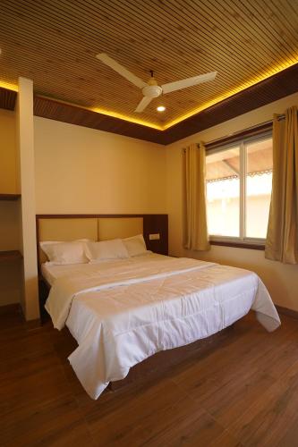 a bedroom with a large white bed with a ceiling at khopoli resort in Khopoli