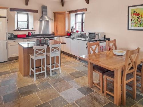 a large kitchen with a wooden table and a table and chairs at Jacks Barn - Hssu in Welcombe