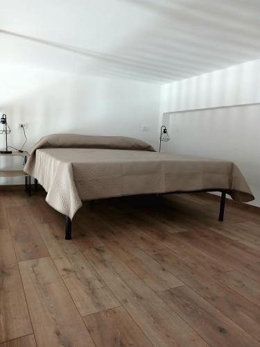 a large bed in a white room with a wooden floor at A Casuzza in Balestrate