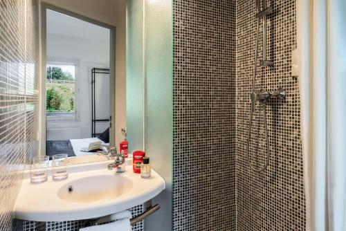 a bathroom with a sink and a shower with a mirror at The Originals Access, Halt'Hotel, Clermont Agnetz in Agnetz