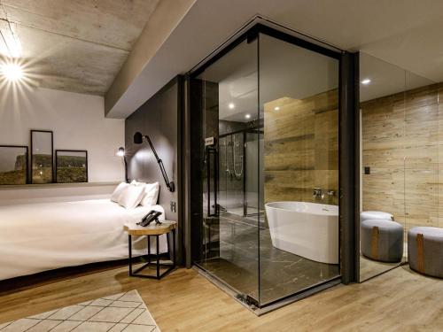 ein Schlafzimmer mit Badewanne und Bett und Bett und Dusche in der Unterkunft Novotel Criciuma in Criciúma