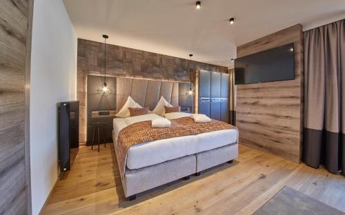 a bedroom with a large bed and a desk at Hotel Hasenauer 4 Sterne Superior in Saalbach-Hinterglemm