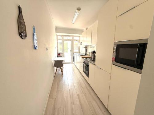 a kitchen with white cabinets and a wooden floor at Estoril 2 bd by the Beach in Estoril