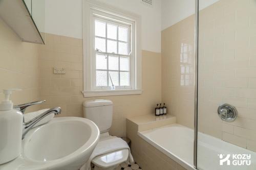 a bathroom with a toilet and a sink and a tub at KozyGuru | MacMahons Point | Harbour Hideaway in Sydney