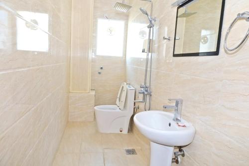 a white bathroom with a sink and a toilet at Alpha Suites Salalah in Salalah