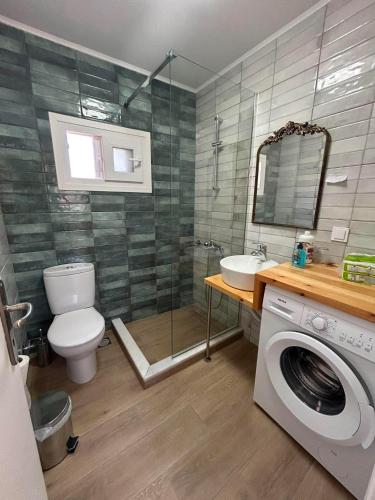 a bathroom with a toilet a sink and a washing machine at Plomari Rum Evi in Plomari