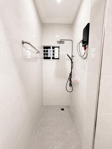 a white bathroom with a shower with a glass door at Maatambaba Homes in Tamale