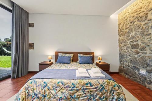 a bedroom with a bed with a stone wall at Casa de Férias Da Padroa in Braga