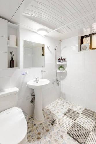 a white bathroom with a toilet and a sink at Pachira House in Seoul