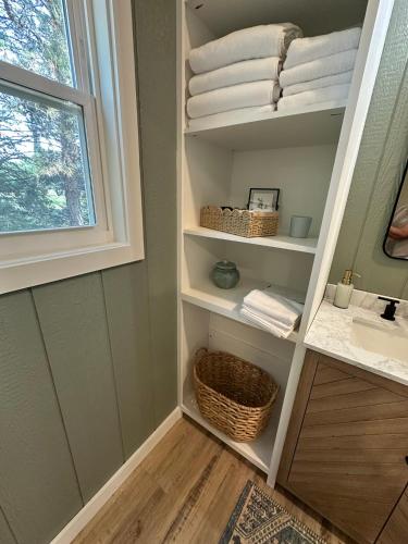 a bathroom with a sink and a shelf with towels at 5 Oaks Casita in Abilene