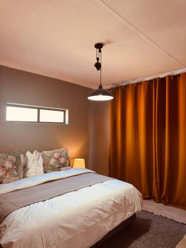 a bedroom with a bed and a yellow curtain at The Leafy Stay in Rundu