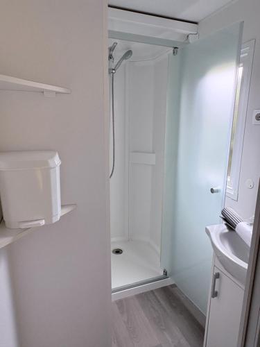 a white bathroom with a shower and a sink at Bungalow Camping 4 étoiles in Messanges
