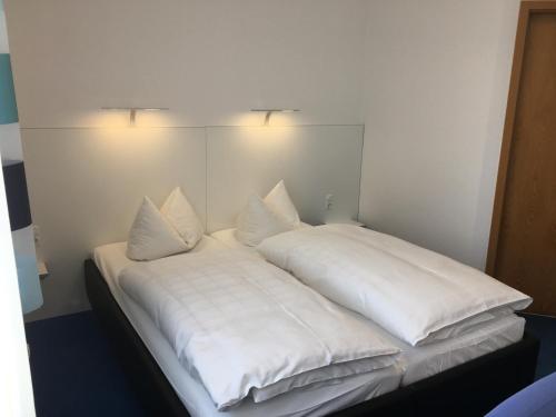 a bed with white sheets and pillows on it at Hotel & Restaurant Park Cafe ISA in Erfurt
