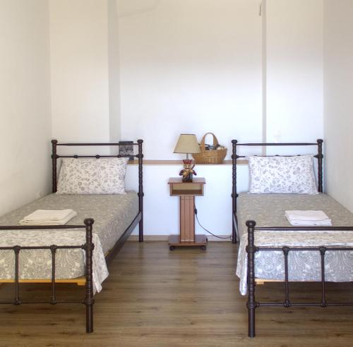 two beds in a room with a lamp on a table at Rosalie Home - Aegean Deck in Tinos