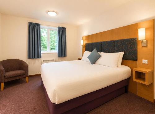 a hotel room with a large bed and a chair at Middleton Inn, Manchester in Manchester