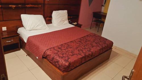 a bedroom with a large bed with a red blanket at Hôtel amsterdam in Douala