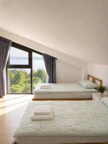 two beds in a room with a large window at Afremar Estate in Nea Fokea