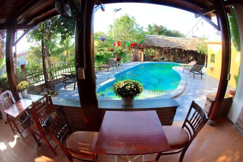 a patio with a table and chairs and a swimming pool at Tam Coc Riverside Bungalow in Ninh Binh