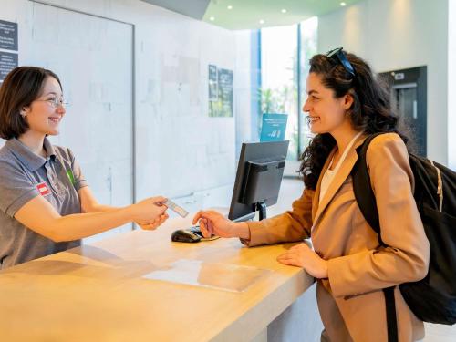 two women are standing at a counter talking at ibis Styles Sorocaba Santa Rosalia in Sorocaba