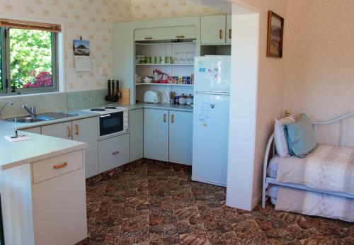 a kitchen with white cabinets and a white refrigerator at Llanerchymedd in Taihape