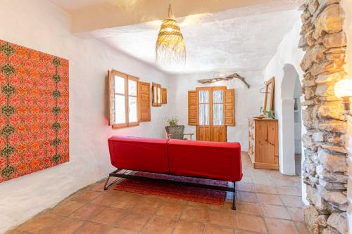 a red couch in a room with a stone wall at Casa Lucía - Off grid vakantiehuisje - Puerto Mika in Torviscón