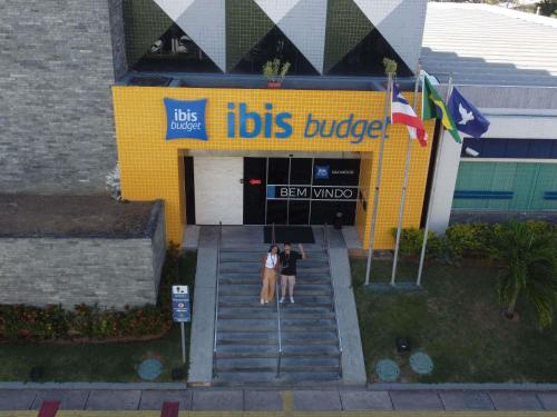 two people standing in front of a bus building at Ibis Budget Salvador in Salvador