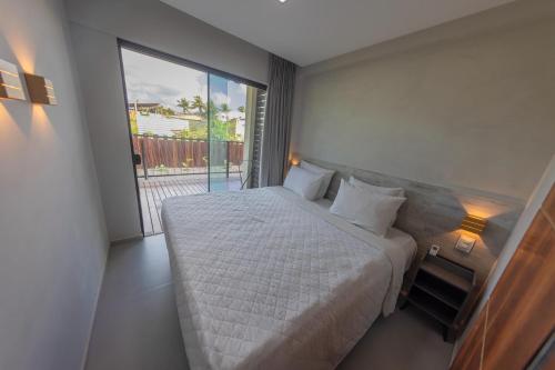 a bedroom with a white bed and a large window at Flats do Cuca in Fernando de Noronha