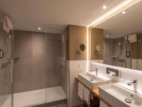 a bathroom with a shower and a sink and a tub at Mercure Parkhotel Mönchengladbach in Mönchengladbach