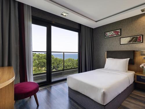 a bedroom with a bed and a large window at Mövenpick Hotel Trabzon in Trabzon