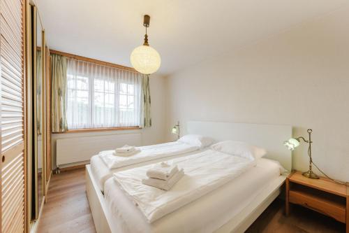 a bedroom with a large white bed with towels on it at Alpine Apartment by Carista Homes in Habkern
