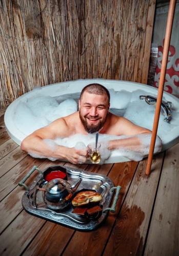 a man laying in a bath tub with a tray of food at Юрта в аренду in Almaty