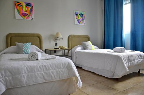 1 dormitorio con 2 camas con sábanas blancas y cortinas azules en Hotel Santa Rosa en Olavarría