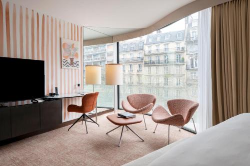 a hotel room with a bed and two chairs and a television at Renaissance Paris Arc de Triomphe Hotel in Paris