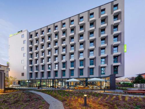 a hotel building with tables and umbrellas in front of it at ibis Styles Kraków Centrum in Krakow