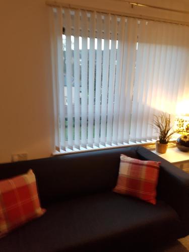 a couch with two pillows sitting in front of a window at Bathgate Contractor and Business Apartment in Bathgate