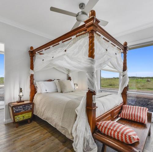 a bedroom with a canopy bed with a fan at Luxurious Home on the Beachside in Port MacDonnell