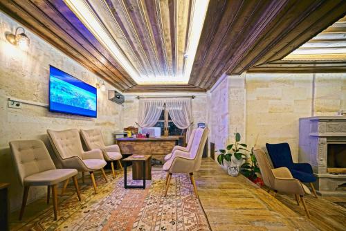 a room with chairs and a table and a tv at Flavia Cappadocia Hotel in Uçhisar