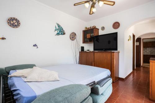 a bedroom with a bed and a flat screen tv at Apartamento Vargas in Monte Gordo