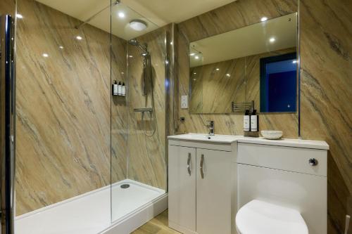 a bathroom with a shower and a toilet and a sink at Old Hunstanton Le Strange Arms Hotel in Hunstanton